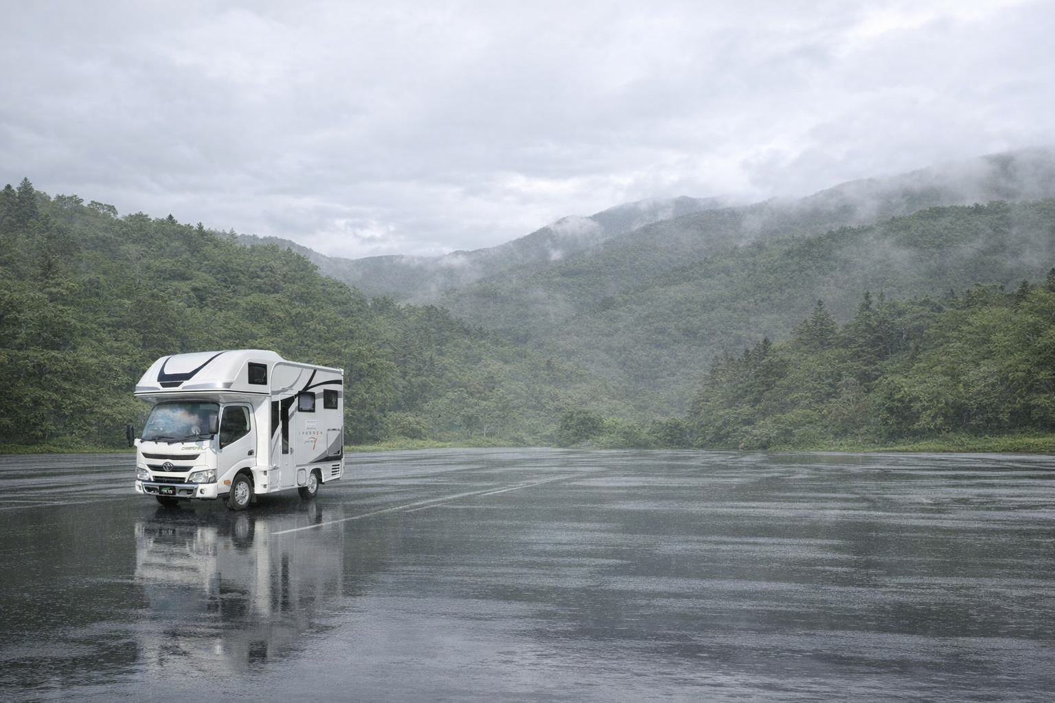 雨の中、山を背景に停まるキャンピングカー