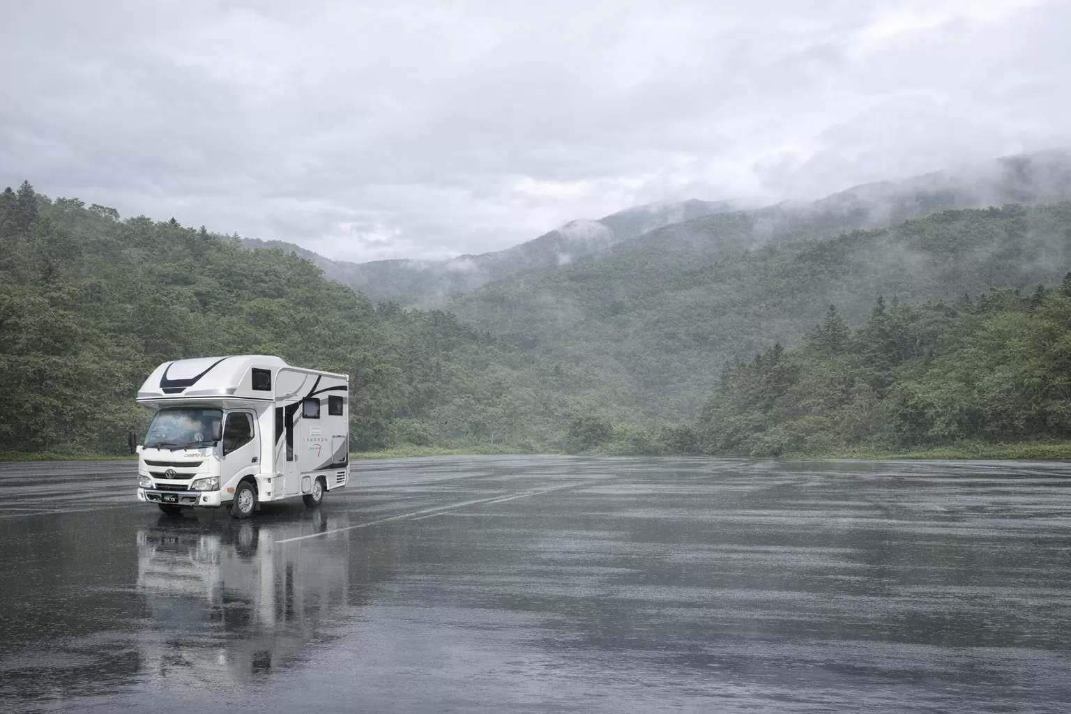 雨の中、山を背景に停まるキャンピングカー