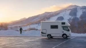 冬の北海道、雪山を背景に駐車場へ停めたキャンピングカーのイメージ写真