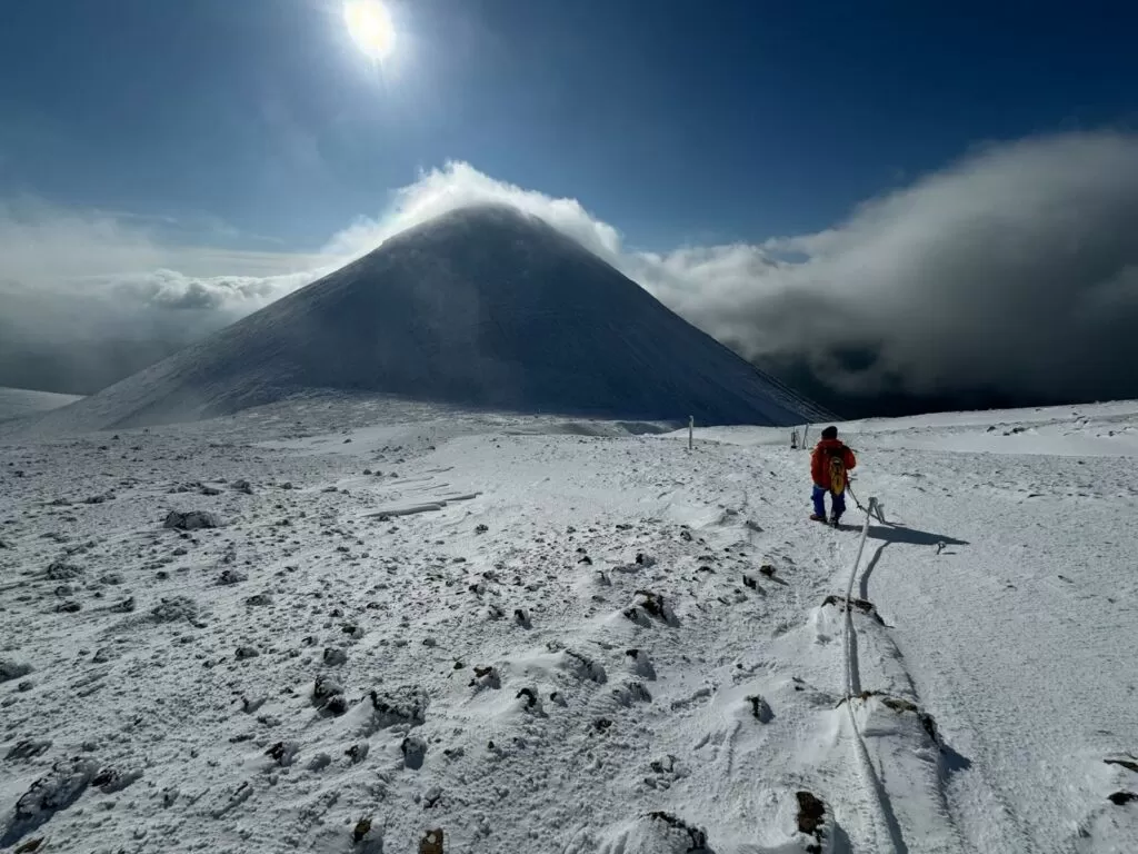 雪の阿寒富士と歩く人