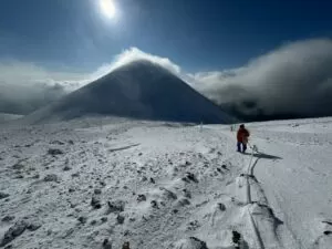 雪の阿寒富士と歩く人