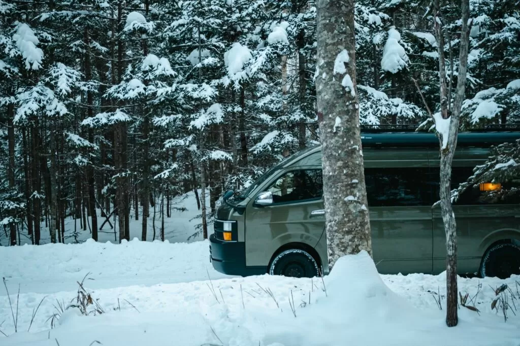 雪の林に停まるMoving Innのキャンピングカー