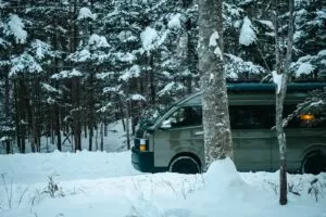 雪の林に停まるMoving Innのキャンピングカー