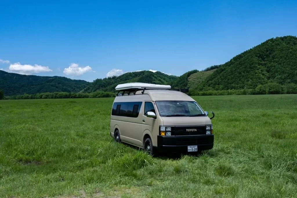 停在草原上、附車頂帳篷的米色露營車