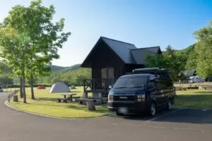 北海道のキャンプ場の芝生サイトに停まったキャンピングカーとコテージ（釧路・夏）