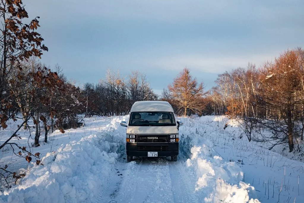 雪を掻いた道に停まるキャンピングカー(夕方の光)