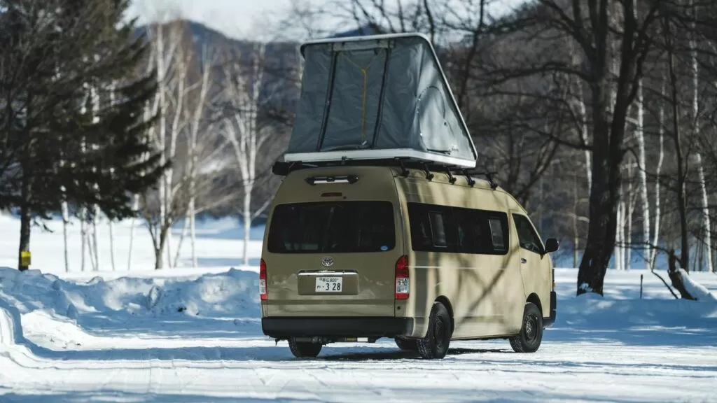 雪の中に停まるルーフテント付きのキャンピングカー