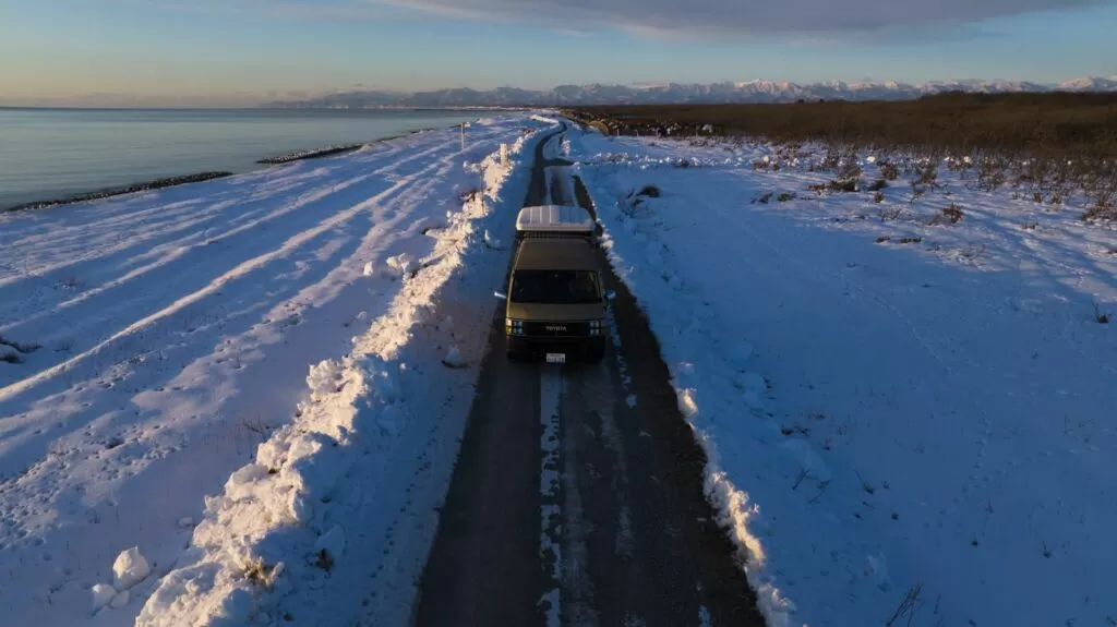 雪原の中の一本道を走るキャンピングカー