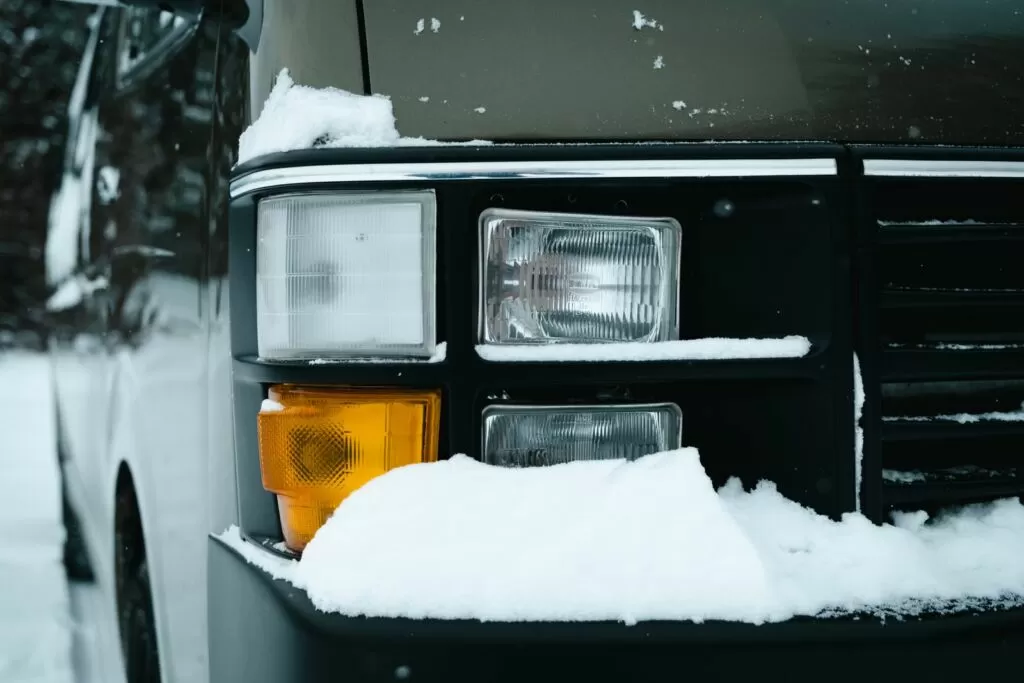 ライトのまわりに雪が積もった車の前面