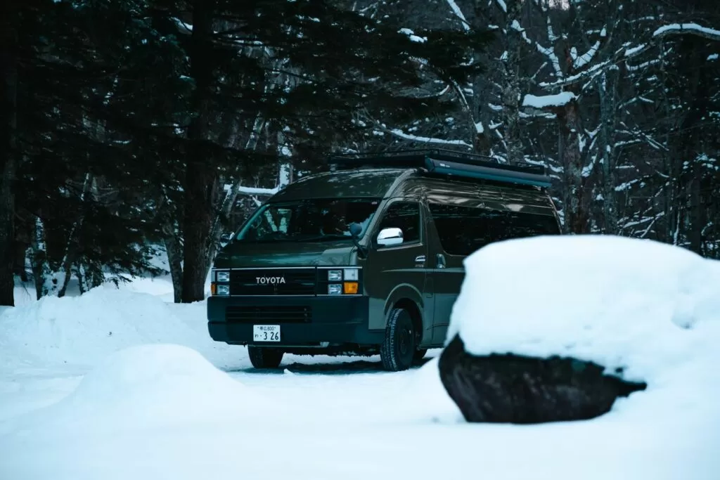 雪の積もった林の中に停めたキャンピングカー